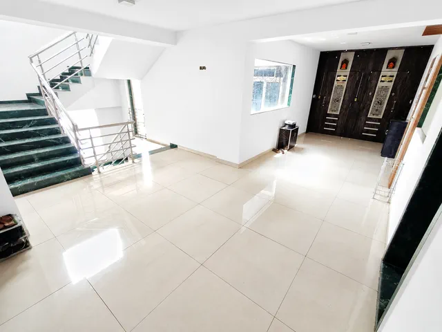 Wide tiled landing at the head of the green-marble stairs, two flat doors at the far end — Dhruva