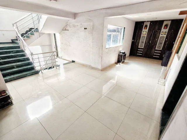 Green-marble steps and a steel railing meeting the tiled landing on a typical floor — Dhruva