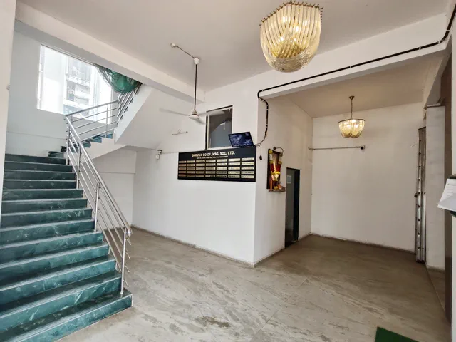 Green-marble staircase and steel railing rising from the entrance lobby past the name board — Dhruva, Karanjade