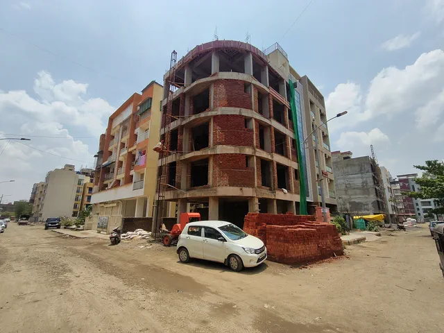 The full height of the shell against a clear sky, brick stacked ready at the base — Ishaan, Karanjade