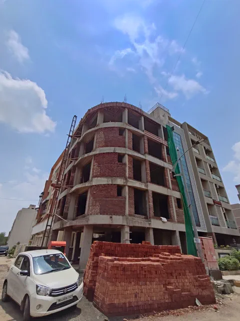 Seen at an angle from the unmade road, brickwork rising between the concrete floors — Ishaan, Karanjade