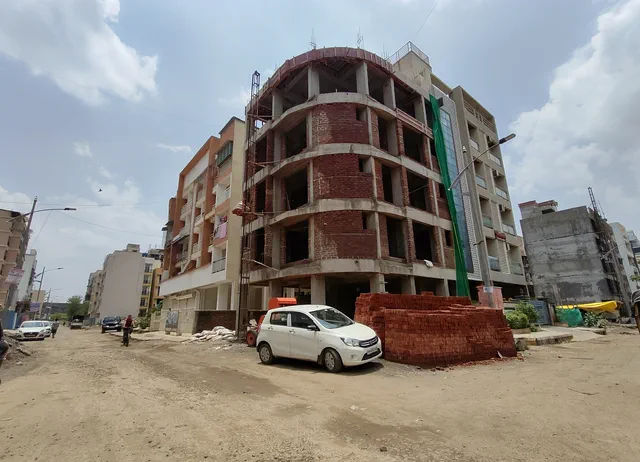 The corner plot from further down the road, the frame still open to the sky at the top — Ishaan, Karanjade