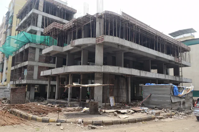 Another face of the frame from the kerbside, the neighbouring buildings pressing right up to it — Prithvi, Karanjade
