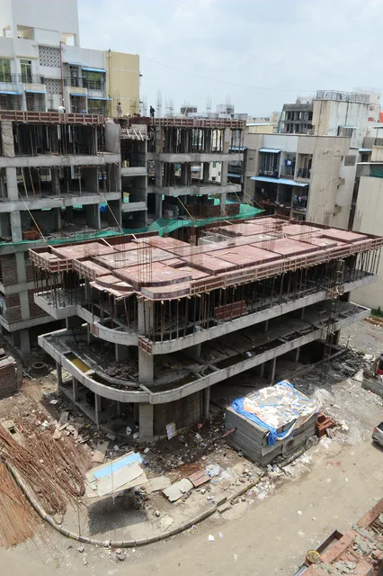 The unfinished top floor closed in by neighbours on every side, seen from above — Prithvi, Karanjade