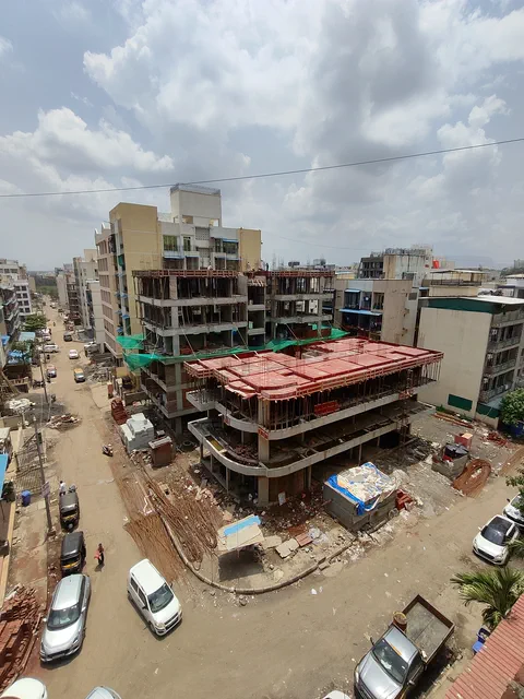 Closer in on the unfinished floors, the parked street and the rooftops running away behind — Prithvi, Karanjade