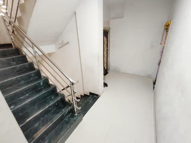 Green-marble steps and a steel railing climbing past a grilled window on a typical floor — Rudra