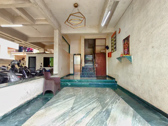 Green-marble floor, notice board and a small shrine shelf in the entrance lobby — Rudra, Karanjade