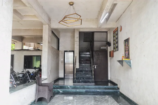 Stainless-steel lift door beside the staircase, under the lobby's brass pendant light — Rudra