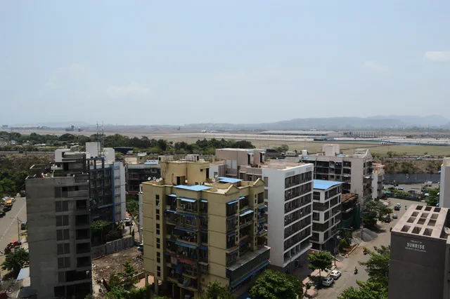 Apartment blocks close below, the airfield and the hills laid out behind them — Shaurya, Karanjade