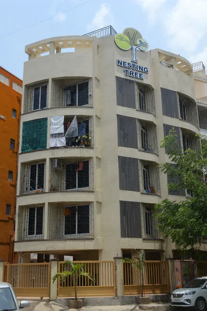 The cream elevation behind its yellow boundary railing, name board on the parapet above — Shaurya, Karanjade