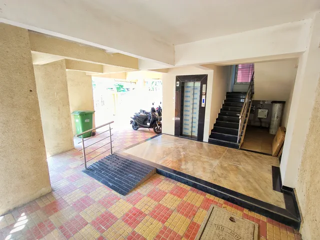 The ramp and railing up to the lift and stairs, checkered tiles across the parking level — Shaurya