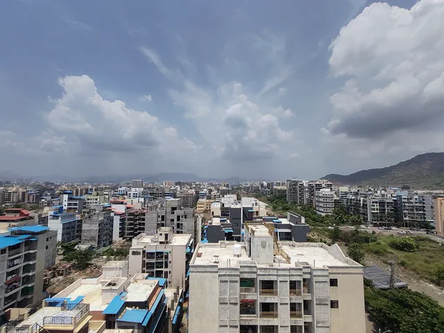 Cumulus building over the neighbourhood rooftops, the town running out to the hills — Shikhar, Karanjade
