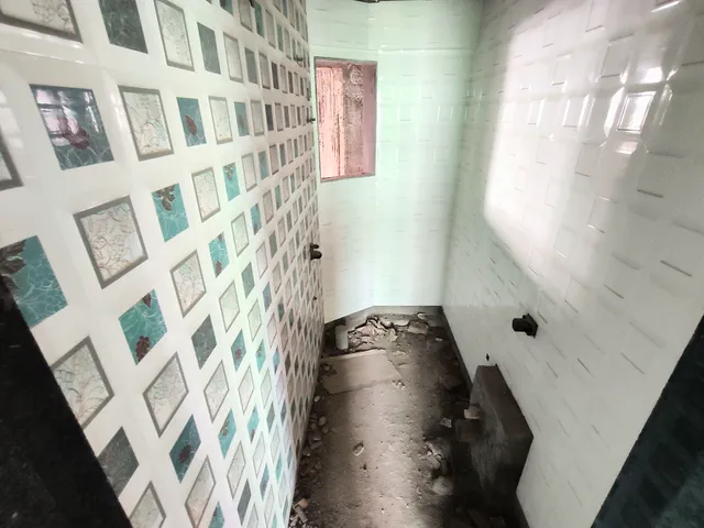 Bathroom under fit-out: a patterned tile feature wall, plain white tiles and a bare floor — Shikhar